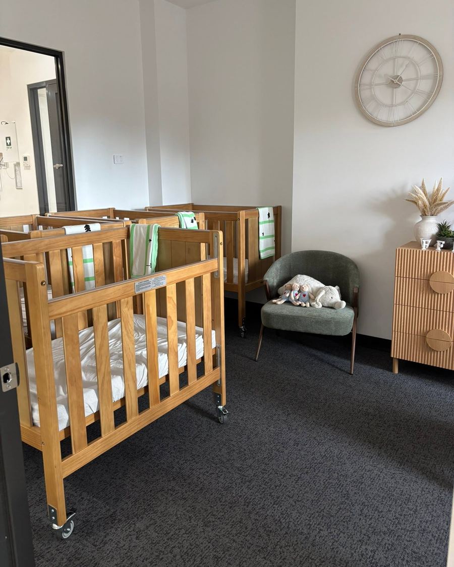 Timber cots and a feeding chair in the Yuri sleep room